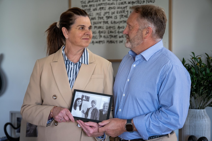 A couple takes a family photo and looks at each other. 