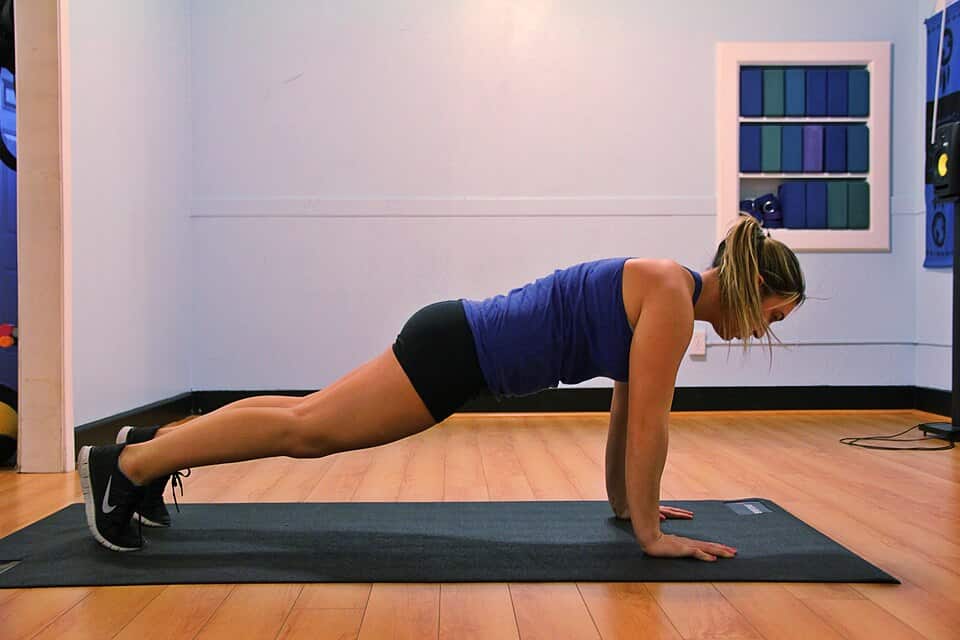 Plank exercise performed on a yoga mat in a fitness studio.