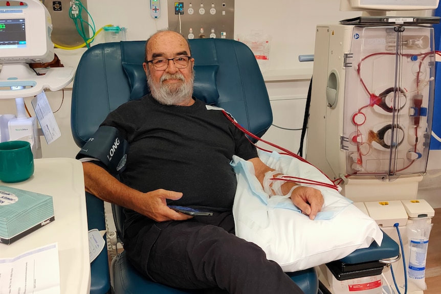 A 72-year-old man sits with multiple lines running through his arm and upper body.