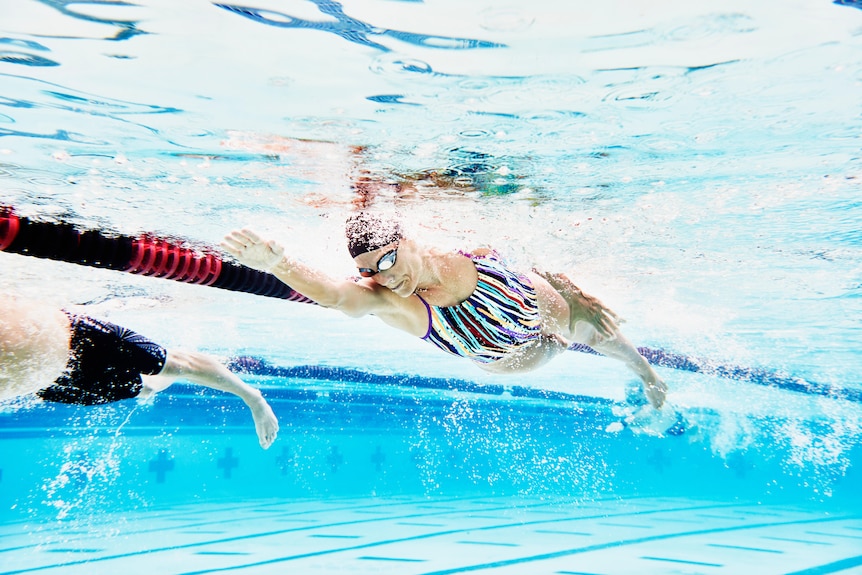 Underwater view of mature female athlete swimming during exercise.