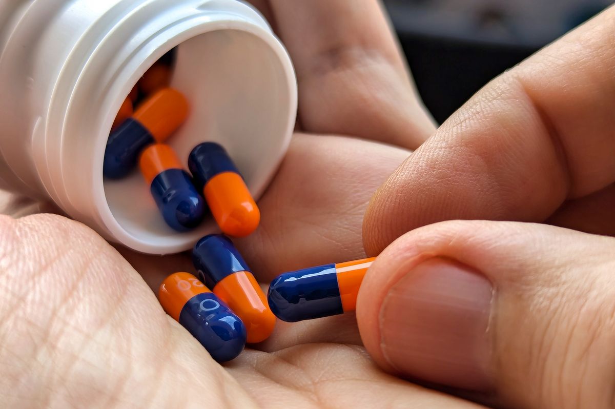 A man holds an omeprazole pill in his hand