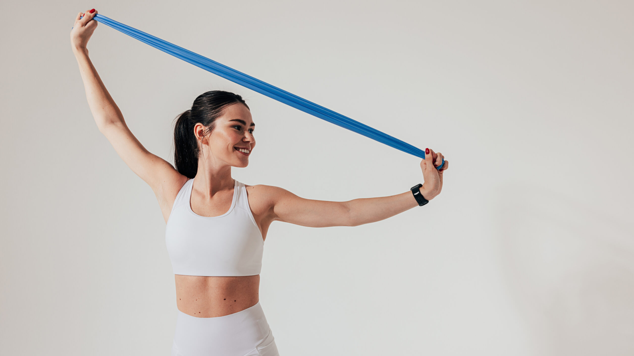 A woman stretches a resistance band over her head