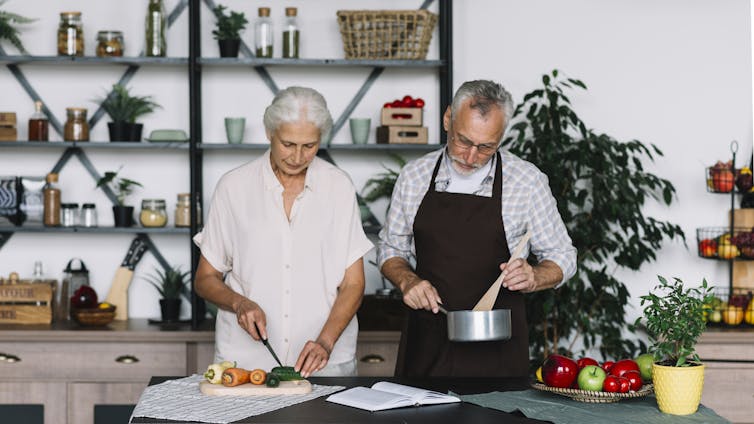 A man and a woman with gray hair prepare food