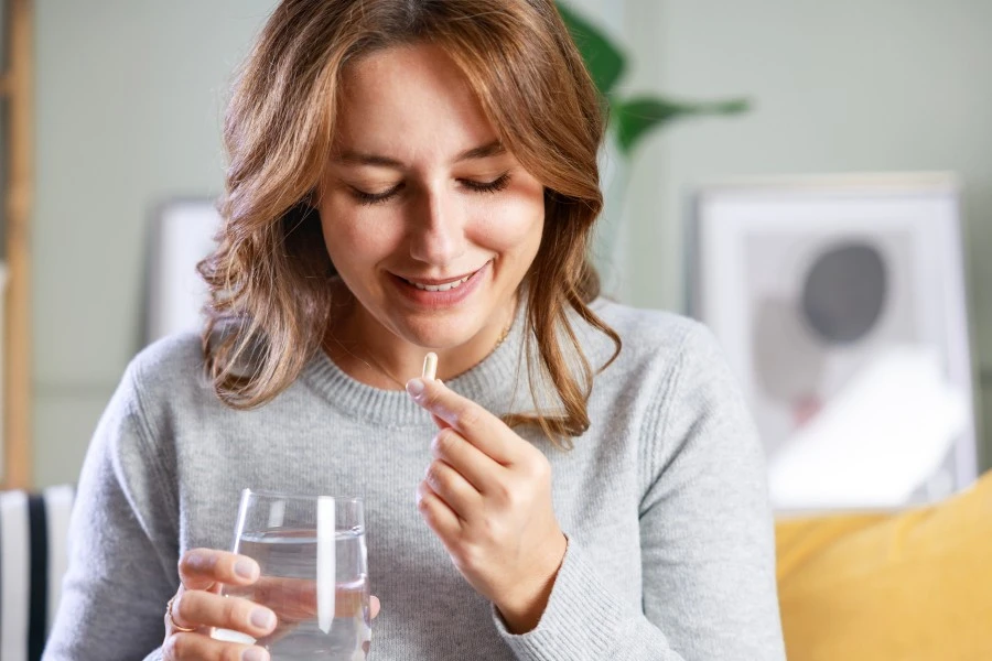 The woman takes the pill with a glass of water.